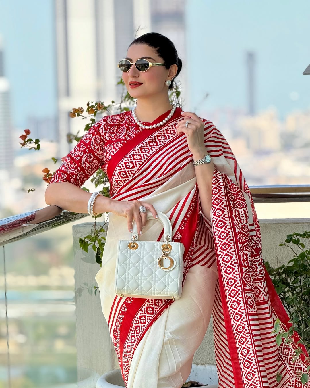 Kawaii red and white block print saree worn by woman with pearl jewelry and white handbag